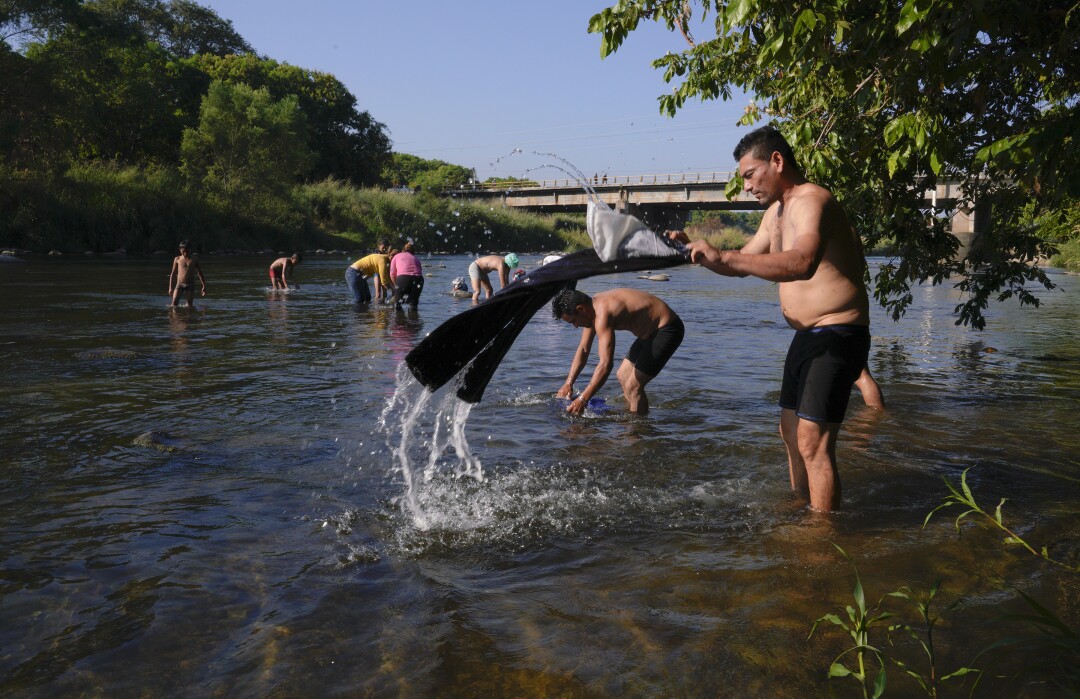 Hombres y mujeres hacen una breve pausa en su viaje hacia el norte para bañarse en el río en Tapachula